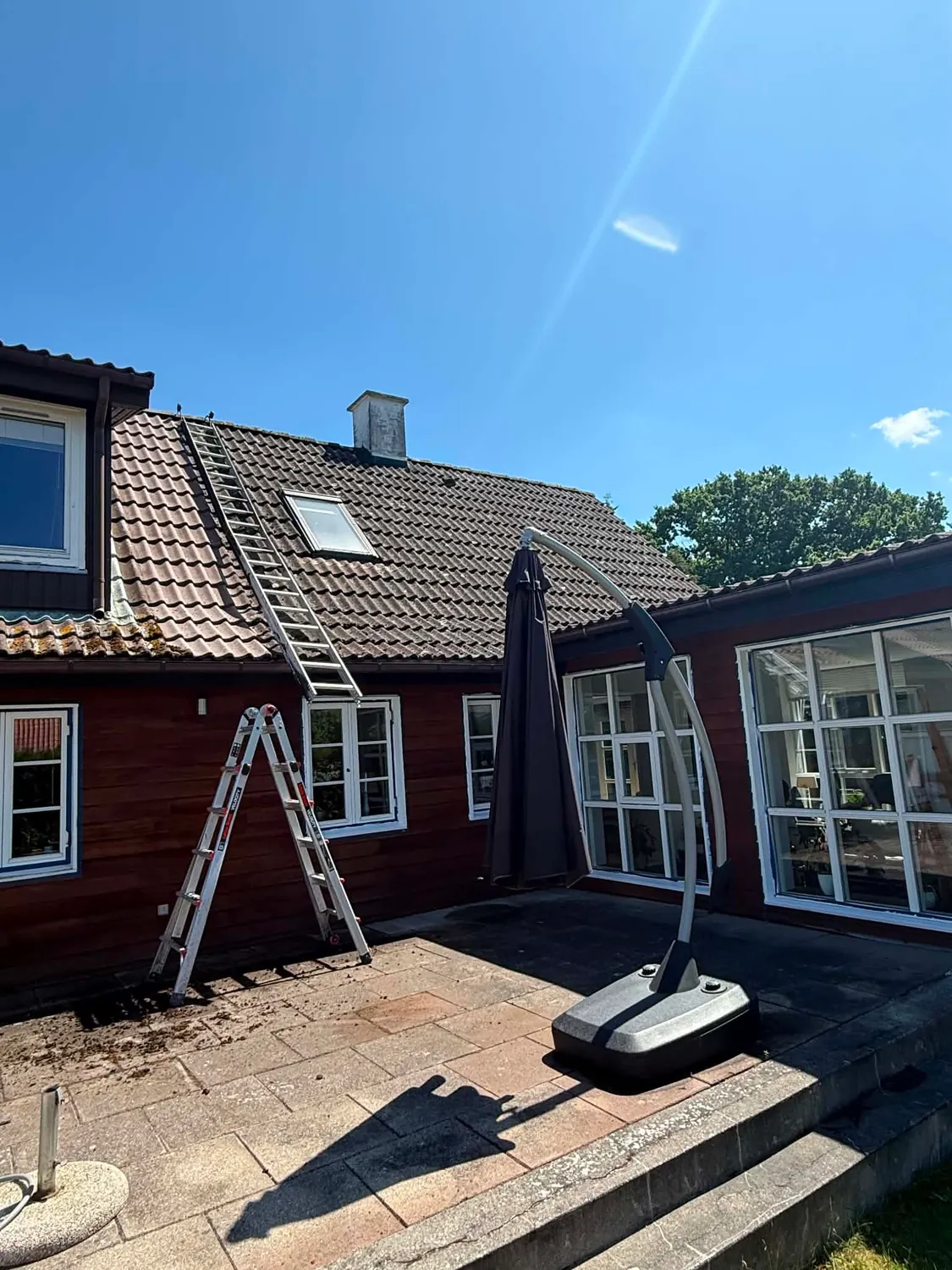 Stige op ad tagfladen og den roterende lavtryksrenser parkeret på terrassen, mens mørkt mos og alger fra taget ligger på fliserne